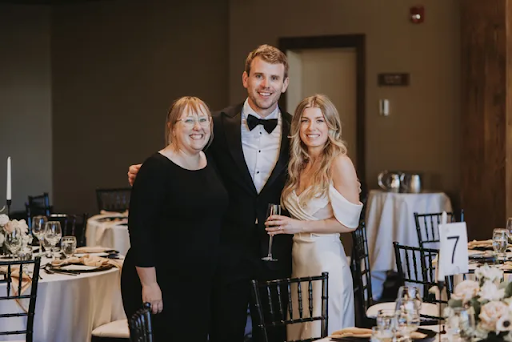 bride and groom are posing for a picture with their mother at their wedding reception.