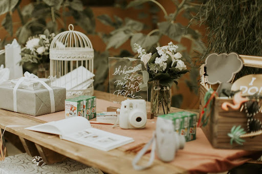 A wooden table topped with a book, a camera, a bird cage , and flowers. Photo from Rochelle and Josh’s wedding